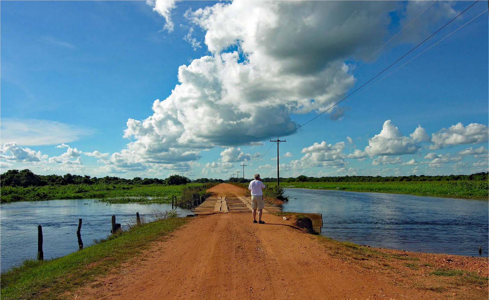 Estrada pantaneira com águas e céu azul